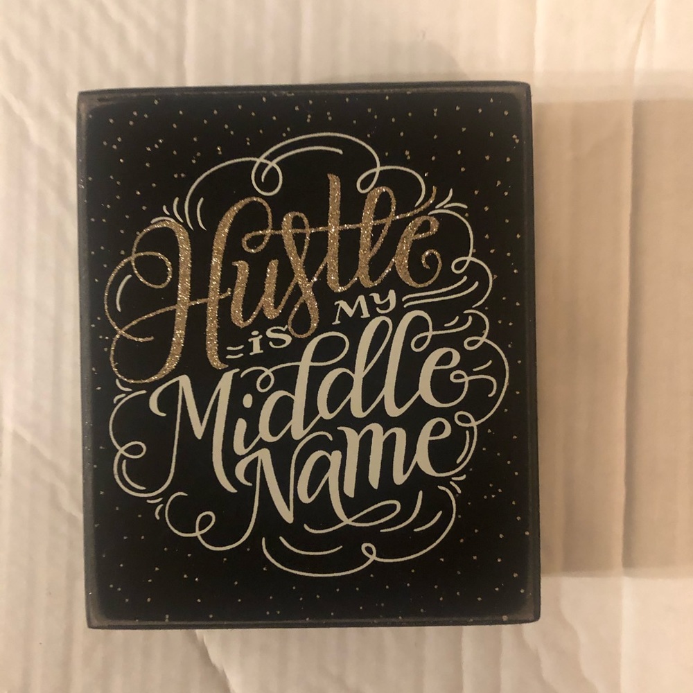 Decorative stand. says “hustle is my middle name”